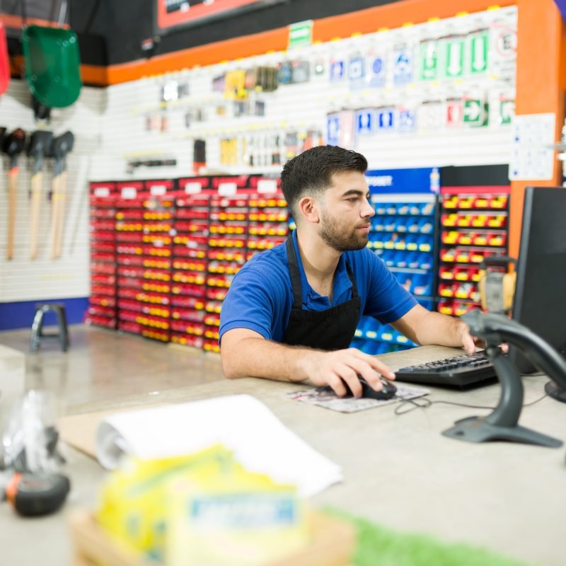Concentrated hardware store employee typing on the computer